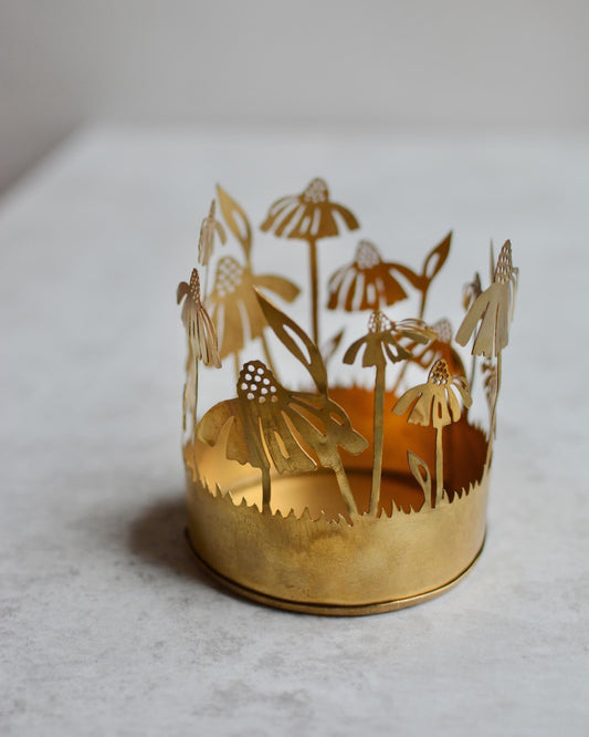 Brass tealight candle holder with floral design on a white background.