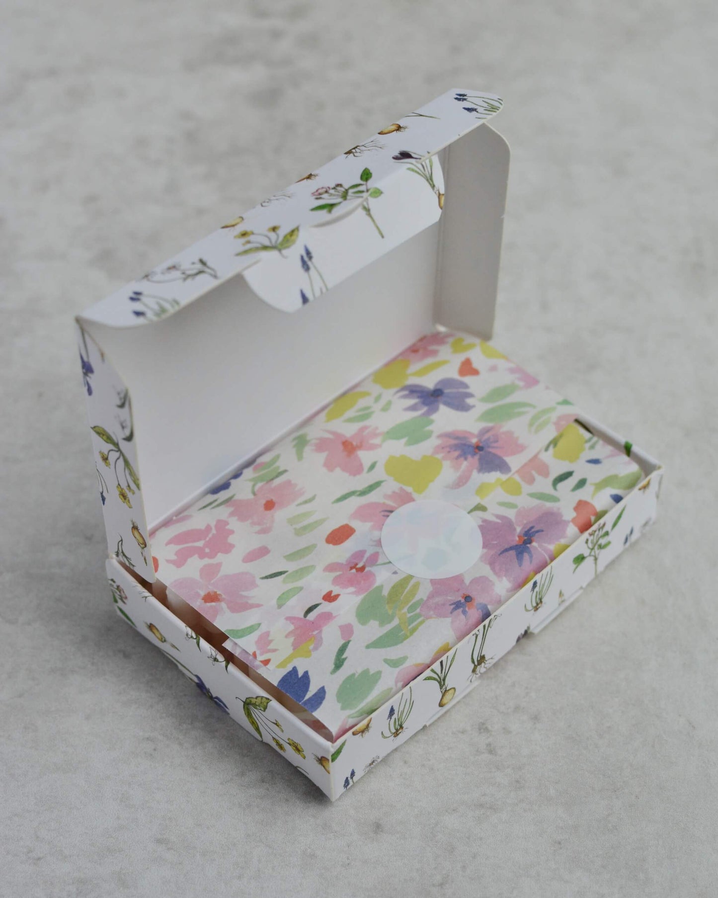 Floral-patterned box of soy wax melts, on a grey surface.