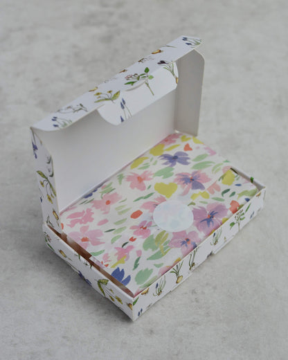 Floral-patterned box of soy wax melts, on a grey surface.