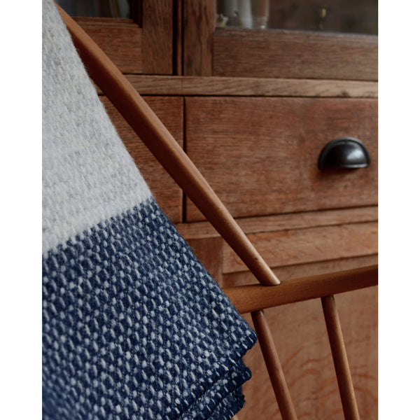 Close up photograph of a Tweedmill light grey and navy cross weave wool throw on chair.